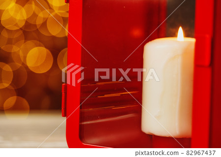 Christmas red lantern with burning candle on wooden table 82967437
