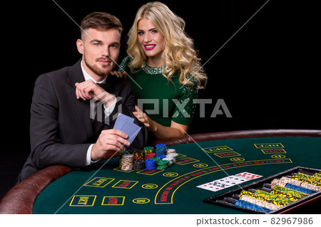 View of young, confident, man with the lady while he's playing poker game. View of young, confident, man with the lady while he's playing poker game. 82967986