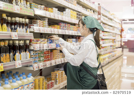 A female employee with a mouse shield who manages products at a supermarket 82970519