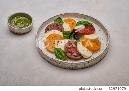 Caprese salad with red and yellow tomatoes, pesto, basil and mozzarella cheese Caprese salad with red and yellow tomatoes, pesto, basil and mozzarella cheese 82971079