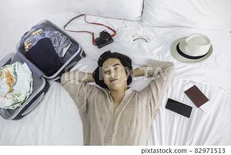 Portrait of young asian man traveler prepare suitcase for holiday vacation. Top overhead view of couple of tourists lying on bed in hotel room. Asian backpacker travel lifestyle concept banner Portrait of young asian man traveler prepare suitcase for holiday vacation. Top overhead view of couple of tourists lying on bed in hotel room. Asian backpacker travel lifestyle concept banner 82971513