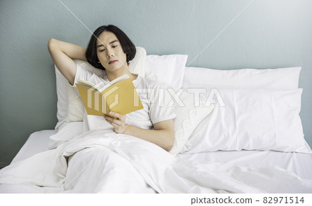 Portrait of handsome young asian man with enjoy reading book in white bed room modern apartment. Asian guy sleep resting, good night sleep, education sleepless concept panoramic banner Portrait of handsome young asian man with enjoy reading book in white bed room modern apartment. Asian guy sleep resting, good night sleep, education sleepless concept panoramic banner 82971514