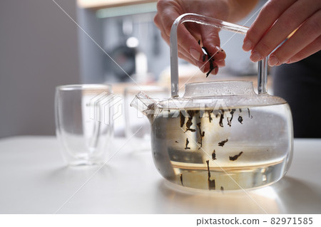 Woman falls asleep tea leaves in transparent glass teapot with hot water Woman falls asleep tea leaves in transparent glass teapot with hot water 82971585
