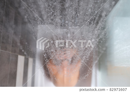 Woman sits in bathtub, water is poured on top of back closeup 82971607