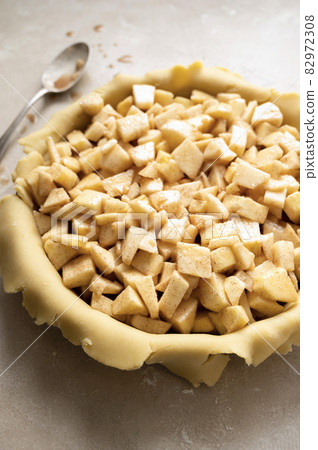 Raw Tart dough, shortcrust pastry with cutted apples, in ceramic tart pan. Baking an apple rustic pie. Step by step recipe. 82972308