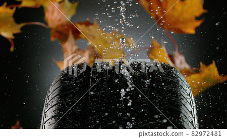 Car Tire with Water Splash and Autumn Leaves. Car Tire with Water Splash and Autumn Leaves. 82972481