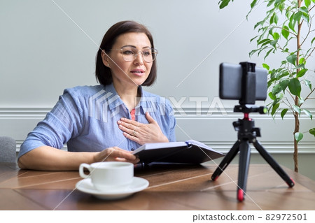 Middle-aged woman teacher, businesswoman working online using smartphone Middle-aged woman teacher, businesswoman working online using smartphone 82972501