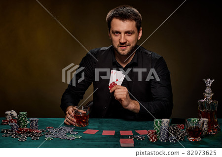 Bearded casino player man playing poker on green table 82973625