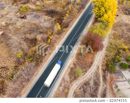 Aerial top view white semi trailer truck delivery shipment cargo courier moving fast on motorway road city urban suburb. Business distribution and logistics express service. Lorry driving highway day Aerial top view white semi trailer truck delivery shipment cargo courier moving fast on motorway road city urban suburb. Business distribution and logistics express service. Lorry driving highway day 82974555