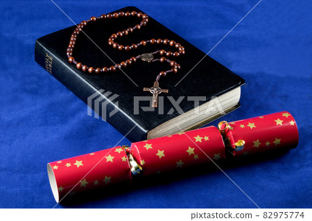 Bible with Rosary and Christmas Cracker on a Blue Cloth Background 82975774