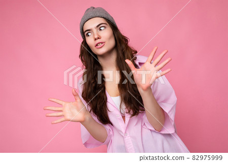 Portrait of young shocked astonished beautiful curly brunette lady with sincere emotions wearing Portrait of young shocked astonished beautiful curly brunette lady with sincere emotions wearing 82975999