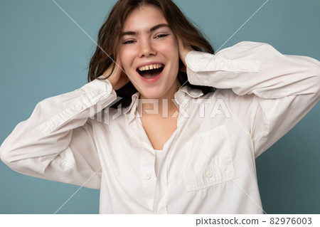 Portrait of beautiful positive cheerful cute smiling young brunette woman in casual white shirt 82976003