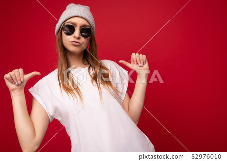 Photo of young positive cool attractive dark blonde woman with sincere emotions wearing casual white Photo of young positive cool attractive dark blonde woman with sincere emotions wearing casual white 82976010