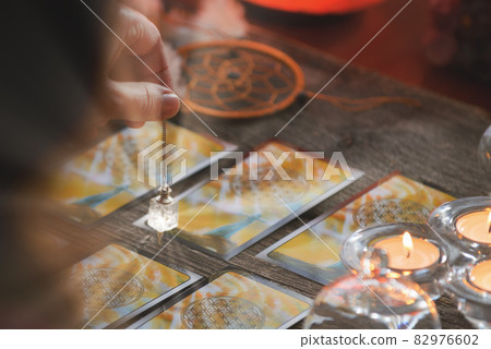Hand with pendulum over tarot cards 82976602
