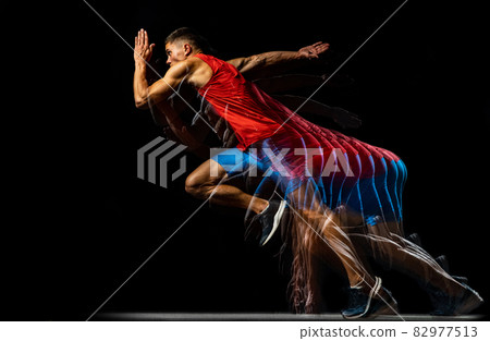 Cropped portrait of young athletic man, professional runner training isolated over black background. Stroboscope effect. In motion Cropped portrait of young athletic man, professional runner training isolated over black background. Stroboscope effect. In motion 82977513