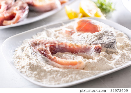 Preparation of fresh fish before frying by wrapping in flour Preparation of fresh fish before frying by wrapping in flour 82978409