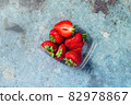 Strawberries in a plastic box on a blue metal background. Eco and Zero Waste Concept 82978867