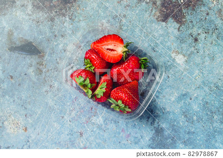 Strawberries in a plastic box on a blue metal background. Eco and Zero Waste Concept 82978867