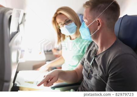 Young married couple flying in airplane wearing protective medical masks Young married couple flying in airplane wearing protective medical masks 82979723