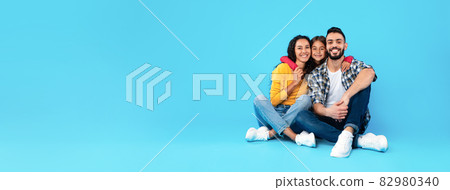 Middle-Eastern Parents and Daughter Embracing Near Empty Space, Blue Background Middle-Eastern Parents and Daughter Embracing Near Empty Space, Blue Background 82980340