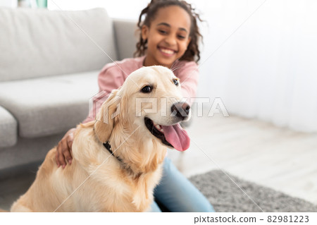 Young black girl playing with dog, selective focus on pet 82981223
