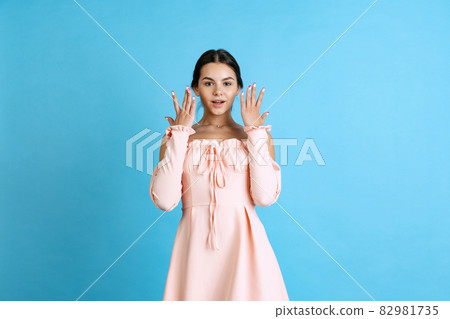 Cropped portrait of young beautiful Caucasian girl posing isolated over blue background Cropped portrait of young beautiful Caucasian girl posing isolated over blue background 82981735