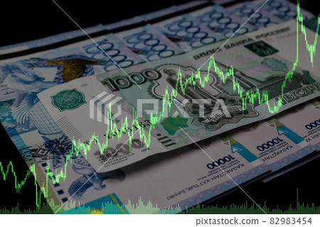 Kazakhstan tenge and Russian ruble on a black background with trading price chart. 82983454