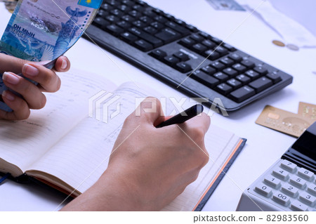 The results of the salary in Kazakhstan. Accountant cashier counts the money in tenge and fills the reports and statements. 82983560
