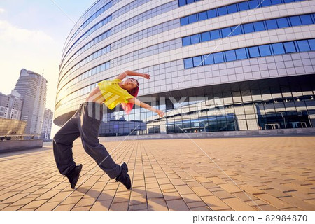 young woman in bright sports clothes and dyed pink hair is dancing in city young woman in bright sports clothes and dyed pink hair is dancing in city 82984870