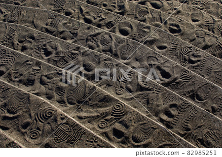 Stairs leading to a sandy beach full of footprints 82985251