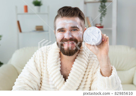 Bearded guy applying anti-wrinkle cream on his face. Skin care and spa for man concept. Bearded guy applying anti-wrinkle cream on his face. Skin care and spa for man concept. 82985610