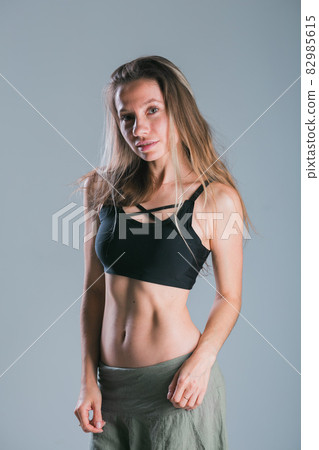 Fitness and diet concept. Portrait of young woman with perfect sporty body and pretty flat abs in sexy sportswear top on gray background. Fitness and diet concept. Portrait of young woman with perfect sporty body and pretty flat abs in sexy sportswear top on gray background. 82985615