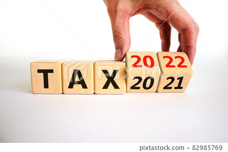 2022 tax new year symbol. Businessman turns wooden cubes and changes words 'Tax 2021' to 'Tax 2022'. Beautiful white background, copy space. Business, 2022 tax new year concept. 82985769