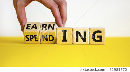 Earning or spending symbol. Businessman hand turns cubes and changes the word 'spending' to 'earning'. Beautiful white background, copy space. Business and earning or spending concept. 82985770