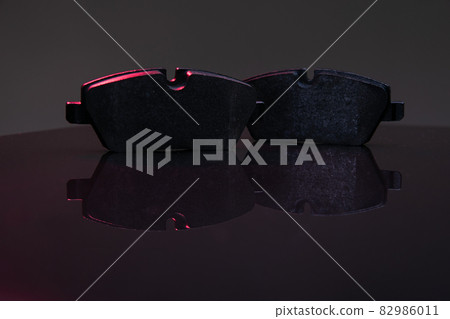 two brake pads on a dark background with red illumination two brake pads on a dark background with red illumination 82986011