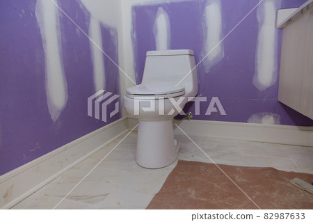 Plumber installing toilet bowl seat in restroom 82987633