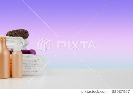 Pile of towels, bottles with shampoo on white table 82987967
