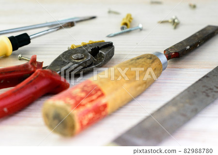 Repair tools on a wooden light background: file, pliers, pliers, screwdriver, screws, bolts Repair tools on a wooden light background: file, pliers, pliers, screwdriver, screws, bolts 82988780