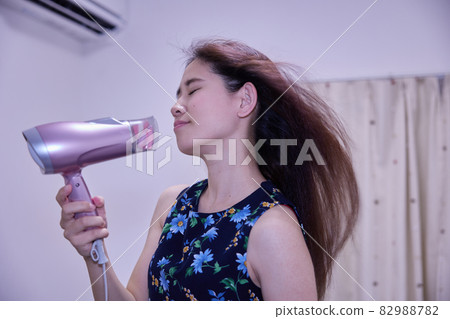 Japanese woman drying her hair with a hair dryer Japanese woman drying her hair with a hair dryer 82988782
