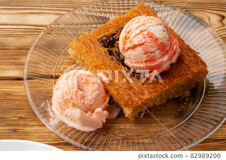 Turkish dessert kunefe served with ice cream on wooden background Turkish dessert kunefe served with ice cream on wooden background 82989200