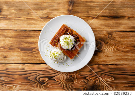 Turkish dessert kunefe served with ice cream on wooden background Turkish dessert kunefe served with ice cream on wooden background 82989223