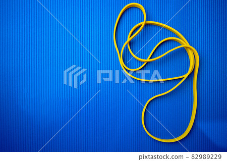 Yellow fitness rope on blue mat background 82989229