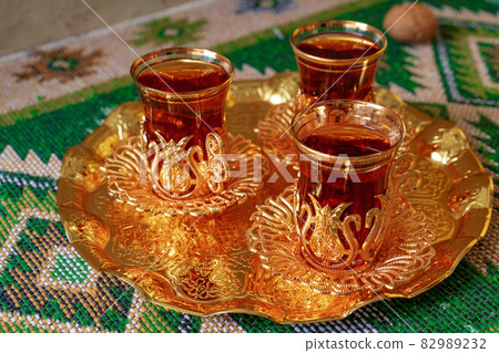 Three cups of black tea on golden oriental tray 82989232