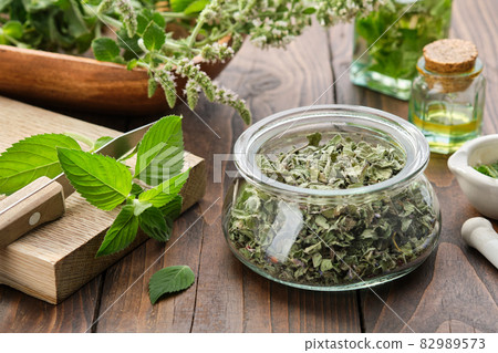 Jar of dried mint leaves. Fresh peppermint leaves on a cutting board. Blossom spearmint medicinal plants, bottles of mint essential oil and infusion. Alternative herbal medicine. Aromatherapy. 82989573