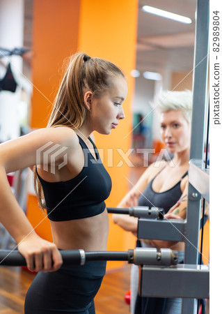A young woman is doing fitness with a trainer at the GYM A young woman is doing fitness with a trainer at the GYM 82989804