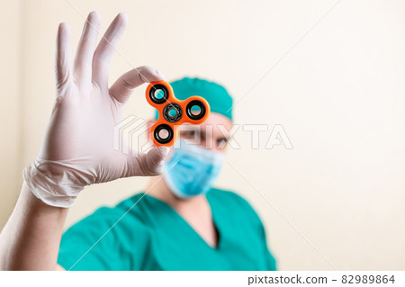 A doctor in a mask and gloves, with a spinner in his hands. 82989864