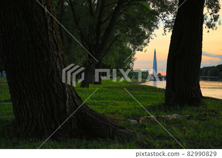 Amazing landscape with trees by the river and a modern skyscraper in the distance. 82990829