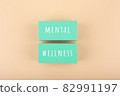 Mental wellness text written on aqua blue toy blocks on bright beige background 82991197