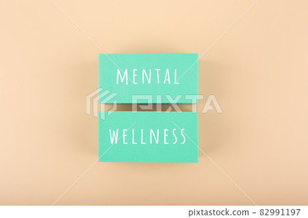 Mental wellness text written on aqua blue toy blocks on bright beige background 82991197