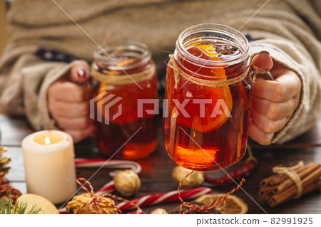 Cup of mulled wine in woman's hands on wooden table 82991925